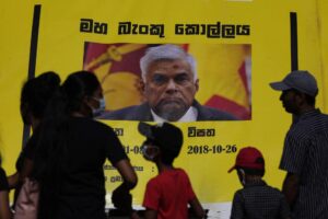 People watch propaganda materials displayed against prime minister Ranil Wickremesinghe outside president Gotabaya Rajapaksa’s office three days after it was stormed by anti government protesters in Colombo, Sri Lanka, Tuesday, July 12, 2022. (AP Photo/Eranga Jayawardena)