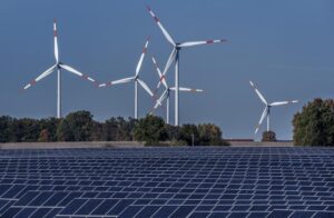 File – Wind turbines turn behind a solar farm in Rapshagen, Germany, Thursday, Oct. 28, 2021. German lawmakers were poised Thursday to approve a major package of reforms aimed at boosting the production of renewable power, as Chancellor Olaf Scholz warned that the country has for too long relied on energy supplies from Russia. (AP Photo/Michael Sohn, File)