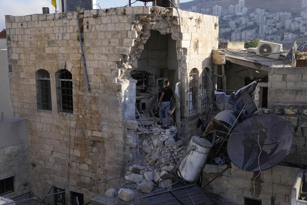A Palestinian boy inspects the damage to a house after Palestinian gunmen were killed in an early morning Israeli military raid in the Old City of Nablus in the West Bank, Sunday, July 24, 2022. Israeli troops shot and killed two Palestinians Sunday, the Palestinian rescue service said, as the Israeli military said it confronted armed men during overnight operations in the West Bank. (AP Photo/Majdi Mohammed)