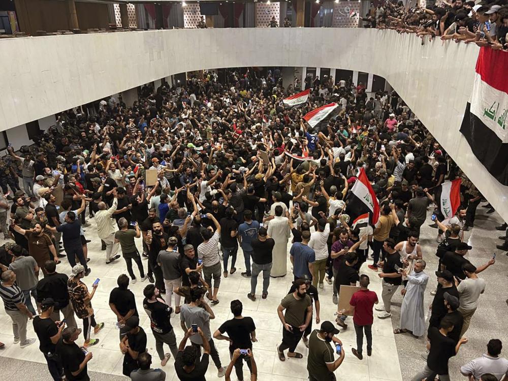 Hundreds of Iraqi protesters breached Baghdad’s parliament in Baghdad, Iraq, Wednesday, July. 27, 2022. The majority of the protesters were followers of influential Shiite cleric Muqtada al-Sadr. The demonstrators, all of them men, were seen walking on tables of the parliament floor, sitting in the chairs of lawmakers and waving Iraqi flags. (AP Photo/Ali Abdul Hassan)