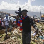 FILE – Barbecue, the leader of the “G9 and Family” gang, stands next to garbage to call attention to the conditions people live in as he leads a march against kidnapping through La Saline neighborhood in Port-au-Prince, Haiti, Friday, Oct. 22, 2021. The group said they were also protesting poverty and for justice in the slaying of President Jovenel Moise. (AP Photo/Odelyn Joseph, File)