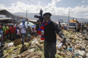 FILE – Barbecue, the leader of the “G9 and Family” gang, stands next to garbage to call attention to the conditions people live in as he leads a march against kidnapping through La Saline neighborhood in Port-au-Prince, Haiti, Friday, Oct. 22, 2021. The group said they were also protesting poverty and for justice in the slaying of President Jovenel Moise. (AP Photo/Odelyn Joseph, File)