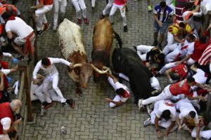 Runners fall during the running of the bulls at the San Fermin Festival in Pamplona, northern Spain, Monday, July 11, 2022. Revellers from around the world flock to Pamplona every year for nine days of uninterrupted partying in Pamplona’s famed running of the bulls festival which was suspended for the past two years because of the coronavirus pandemic. (AP Photo/Alvaro Barrientos)