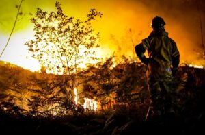 This photo provided by the fire brigade of the Gironde region (SDIS 33) shows a firefighter stands next to wildfire near Landiras, southwestern France, Monday morning, July 18, 2022. France scrambled more water-bombing planes and hundreds more firefighters to combat spreading wildfires that were being fed Monday by hot swirling winds from a searing heat wave broiling much of Europe. With winds changing direction, authorities in southwestern France announced plans to evacuate more towns and move out 3,500 people at risk of finding themselves in the path of the raging flames. (SDIS 33 via AP)
