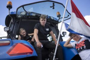 Protesting farmers and their children sit in their tractors at a blockade outside a distribution center for supermarket chain Aldi in the town of Drachten, northern Netherlands, Monday, July 4, 2022. Dutch farmers angry at government plans to slash emissions used tractors and trucks Monday to blockade supermarket distribution centers, the latest actions in a summer of discontent in the country’s lucrative agricultural sector. (AP Photo/Peter Dejong)