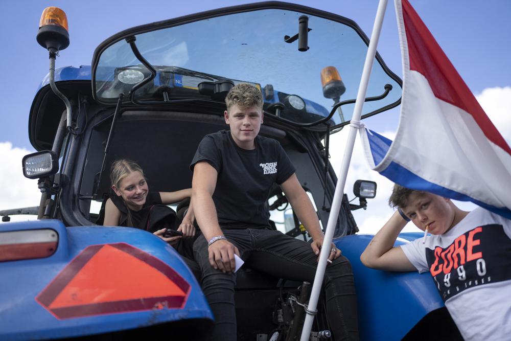 Protesting farmers and their children sit in their tractors at a blockade outside a distribution center for supermarket chain Aldi in the town of Drachten, northern Netherlands, Monday, July 4, 2022. Dutch farmers angry at government plans to slash emissions used tractors and trucks Monday to blockade supermarket distribution centers, the latest actions in a summer of discontent in the country’s lucrative agricultural sector. (AP Photo/Peter Dejong)