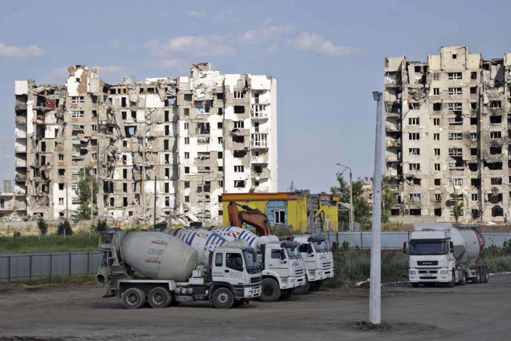 Cement trucks parked at a construction site of an apartment building under construction for residents of Mariupol affected by hostilities, in Mariupol, in territory under the government of the Donetsk People’s Republic, eastern Ukraine, Friday, July 1, 2022. (AP Photo)
