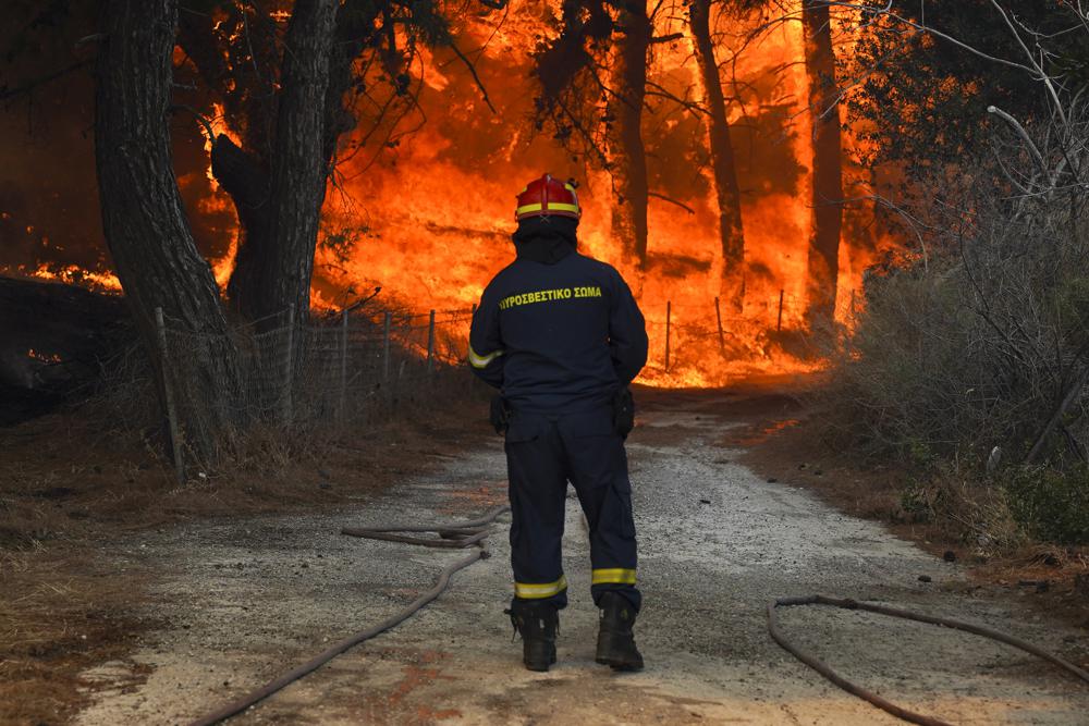A firefighter tries to extinguishes a forest fire near the beach resort of Vatera, on the eastern Aegean island of Lesvos, Greece, Saturday, July 23, 2022. (AP Photo/Yorgos Karahalis)