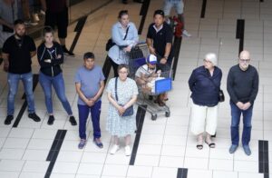People observe a minute’s silence to honour the victims of last week’s shooting as shopping center Field’s reopens, in Copenhagen, Monday, July 11, 2022. Several hundred shoppers and employees have stood for a minute of silence inside the Copenhagen mall where three people were killed when a gunman opened fired eight days ago. (Liselotte Sabroe/Ritzau Scanpix via AP)