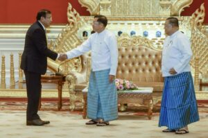 In this photo provided by the Myanmar’s Foreign Ministry, Myanmar State Administration Council Chairman Senior General Min Aung Hlaing, center, shakes hands with Cambodian Foreign Minister and ASEAN Special Envoy to Myanmar Prak Sokhonn, left, and Myanmar Foreign Minister Wunna Maung Lwin, right, during a meeting in Naypyitaw, Myanmar, Thursday, June 30, 2022. (Myanmar’s Foreign Ministry via AP)