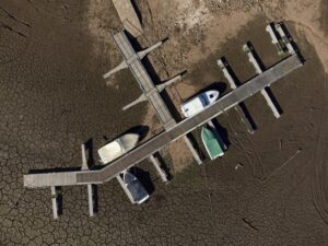 FILE – Pleasure boats tied to a pier rest on dry ground of the water depleted Zezere River due to drought, near Figueiro dos Vinhos in central Portugal, Feb. 17, 2022. Portugal is bracing for a heat wave, with temperatures in some areas forecast to climb as high as 43 degrees Celsius this weekend just as a severe drought grips the country. The Civil Protection Agency, a government body that coordinates official responses to emergencies, is placing crews on high alert Thursday, July 7, 2022 due to the risk of wildfires. (AP Photo/Sergio Azenha, File)