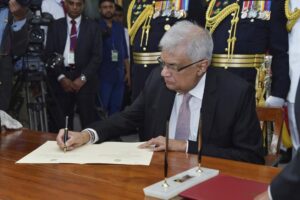 FILE – In this photo provided by Sri Lankan President’s Office, Sri Lanka’s newly elected president Ranil Wickremesinghe, signs after taking oath during his swearing-in ceremony in Colombo, Sri Lanka, Thursday, July 21, 2022. On Friday, he appointed a classmate and ally of ousted President Gotabaya Rajapaksa to be his prime minister and partner in rescuing the country from its predicament. The question is whether they can muster the political heft and enough support from a public fed up with shortages of food, fuel and medicine to get the job done. (Sri Lankan President’s Office via AP, File)