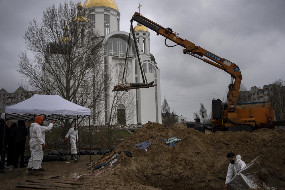 FILE – A crane lifts the corpse of a man from a mass grave to be identified in a morgue, in Bucha, on the outskirts of Kyiv, Ukraine, Sunday, April 10, 2022. Ministers from dozens of nations are meeting on Thursday, July 14, 2022 in the Netherlands to discuss with the International Criminal Court’s chief prosecutor how best to coordinate efforts to bring to justice perpetrators of war crimes in Ukraine. (AP Photo/Rodrigo Abd, File)