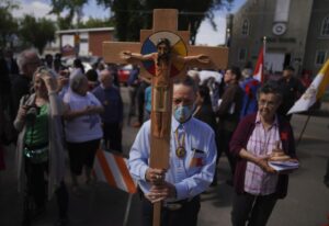 FILE – Elmer Waniandy raises the crucifix as he leads his fellow parishioner into the rededicated and newly renovated Sacred Heart Church of the First Peoples sanctuary, July 17, 2022, in Edmonton, Alberta. Pope Francis’ trip to Canada, which begins Sunday July 24, 2022, to apologize for the horrors of church-run Indigenous residential schools marks a radical rethink of the Catholic Church’s missionary legacy in the Americas, spurred on by the first American pope and the discovery of hundreds of unmarked graves at the school sites. (AP Photo/Jessie Wardarski, File)