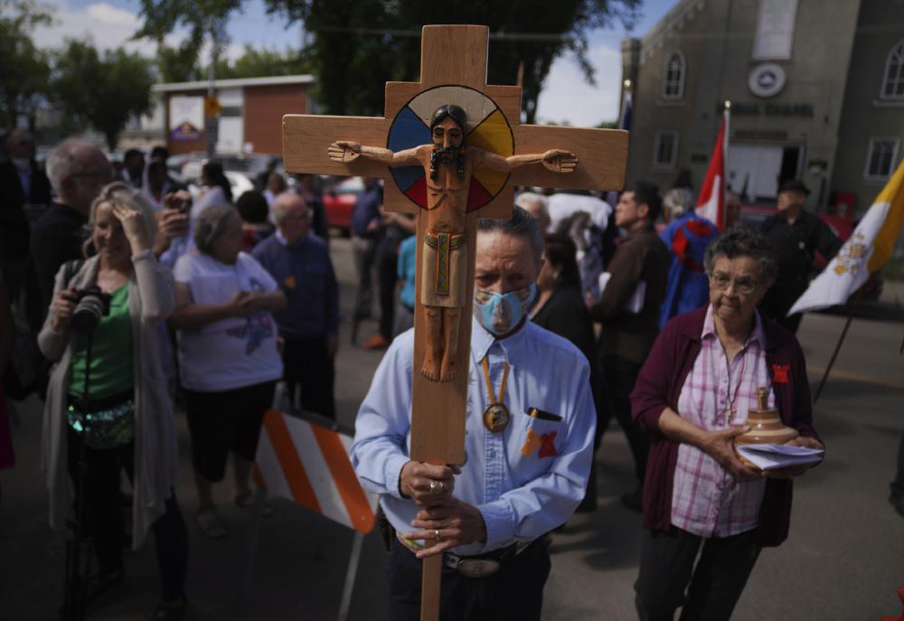 FILE – Elmer Waniandy raises the crucifix as he leads his fellow parishioner into the rededicated and newly renovated Sacred Heart Church of the First Peoples sanctuary, July 17, 2022, in Edmonton, Alberta. Pope Francis’ trip to Canada, which begins Sunday July 24, 2022, to apologize for the horrors of church-run Indigenous residential schools marks a radical rethink of the Catholic Church’s missionary legacy in the Americas, spurred on by the first American pope and the discovery of hundreds of unmarked graves at the school sites. (AP Photo/Jessie Wardarski, File)