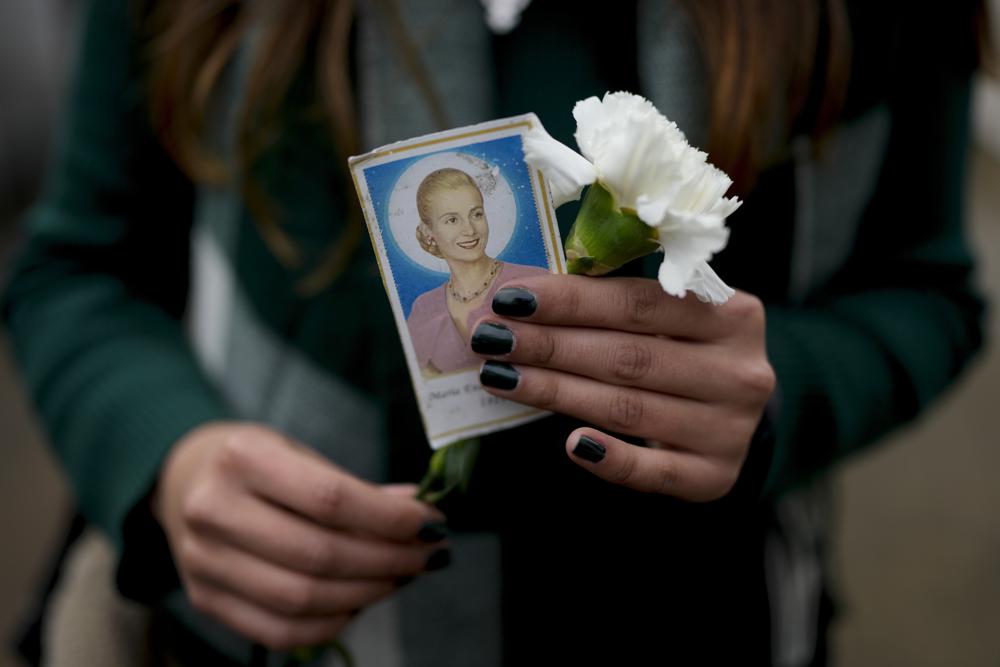 A woman holds a photo of Argentina’s late first lady Maria Eva Duarte de Peron, better known as Evita, as she waits her turn to visit Evita’s tomb in Buenos Aires, Argentina, Tuesday, July 26, 2022. Argentines commemorate the 70th anniversary of the death of their most famous first lady, who died of cancer on July 26, 1952 at the age of 33. (AP Photo/Natacha Pisarenko)