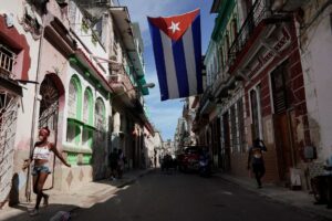 People walk under a Cuban flag hanging in downtown Havana, Cuba, October 8, 2021. REUTERS/Alexandre Meneghini