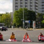Climate activist Lina Schinkoethe, left, and her mother Solvig Schinkoethe, second from left, sit with their hands glued to the ground during a protest with the group Uprising of the Last Generation in Berlin, Germany, Tuesday, June 21, 2022.