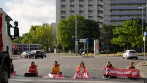Climate activist Lina Schinkoethe, left, and her mother Solvig Schinkoethe, second from left, sit with their hands glued to the ground during a protest with the group Uprising of the Last Generation in Berlin, Germany, Tuesday, June 21, 2022.