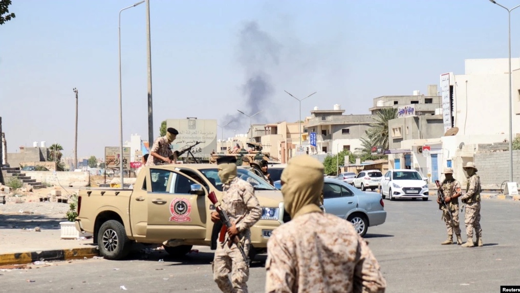Members of the Libyan armed unit, 444 Brigade, backing the Government of National Unity (GNU) and its Prime Minister Abdulhamid al-Dbeibah, set up a checkpoint as smoke rises in the background in Ain Zara area in Tripoli, Libya, July 22, 2022.