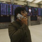 A broker talks on his cell phone while monitoring a stock index on a big screen at the Pakistan Stock Exchange, which responded positively after the news of an International Monetary Fund bailout package, in Karachi, Pakistan, Thursday, July 14, 2022. The IMF said Thursday it had reached a preliminary agreement with Pakistan to revive a $6 billion bailout package for this impoverished Islamic nation, which has been facing a serious economic crisis since last year. (AP Photo/Fareed Khan)