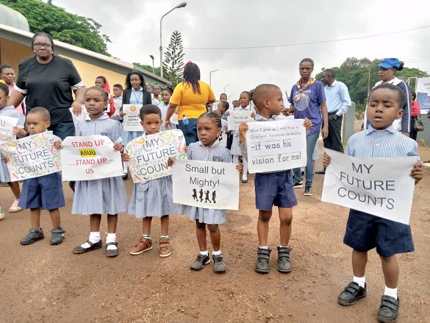 Protesting school children carrying placards in front of OAU