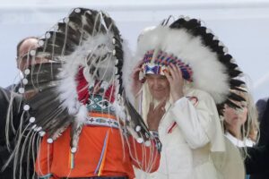 Pope Francis puts on an indigenous headdress during a meeting with indigenous communities, including First Nations, Metis and Inuit, at Our Lady of Seven Sorrows Catholic Church in Maskwacis, near Edmonton, Canada, Monday, July 25, 2022. Pope Francis begins a “penitential” visit to Canada to beg forgiveness from survivors of the country’s residential schools, where Catholic missionaries contributed to the “cultural genocide” of generations of Indigenous children by trying to stamp out their languages, cultures and traditions. Francis set to visit the cemetery at the former residential school in Maskwacis. (AP Photo/Gregorio Borgia)