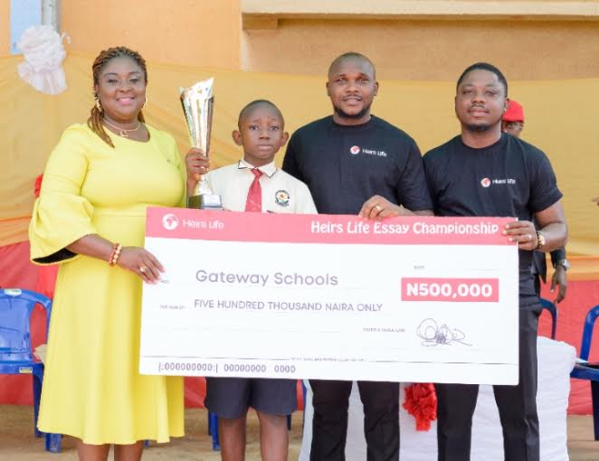 L-R: Proprietress, Gateway Schools, Enugu, Dr Loveline Ndu; Winner, Heirs Life Essay Championship, Ugbomyke Princewill; Communications Manager, Heirs Life Assurance Limited, Timilehin Adebiyi and Head, Retail Sales, Heirs, Olugbenga Osibodu, at the presentation ceremony of Heirs Life Essay Championship Cup at Gateway Schools, Enugu