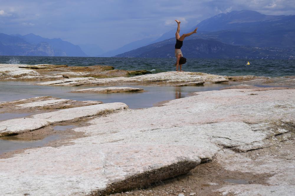 A woman takes a roll on the peninsula of Sirmione, on Garda lake, Italy, Friday, Aug. 12, 2022. Lake Garda water level has dropped critically following severe drought resulting in rocks to emerge around the Sirmione Peninsula. (AP Photo/Antonio Calanni)