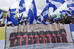 FILE – Anti-government demonstrators hold a banner featuring a group of Catholic cardinals including Nicaraguan Leopoldo Brenes, center right, and a quote from John Paul II that reads in Spanish, “The Church is the first to want peace!”, during a march supporting the Catholic Church, in Managua, Nicaragua, July 28, 2018. The Nicaraguan Catholic Church has been sympathetic toward protesters opposed to President Daniel Ortega’s government. Ortega has responded by accusing some bishops of being part of a plot to overthrow him and calling them “terrorists.” (AP Photo/Alfredo Zuniga, File)