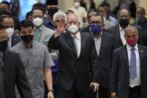 Former Malaysian Prime Minister Najib Razak, center, wearing a face mask, waves as he arrives at Court of Appeal in Putrajaya, Malaysia, Tuesday, Aug. 23, 2022. Najib was sentenced to 12 years in jail by a high court in July 2020, after being found guilty of abuse of power, criminal breach of trust and money laundering for illegally receiving 42 million ringgit ($9.4 million) from SRC International, a former unit of 1MDB. (AP Photo/Vincent Thian)