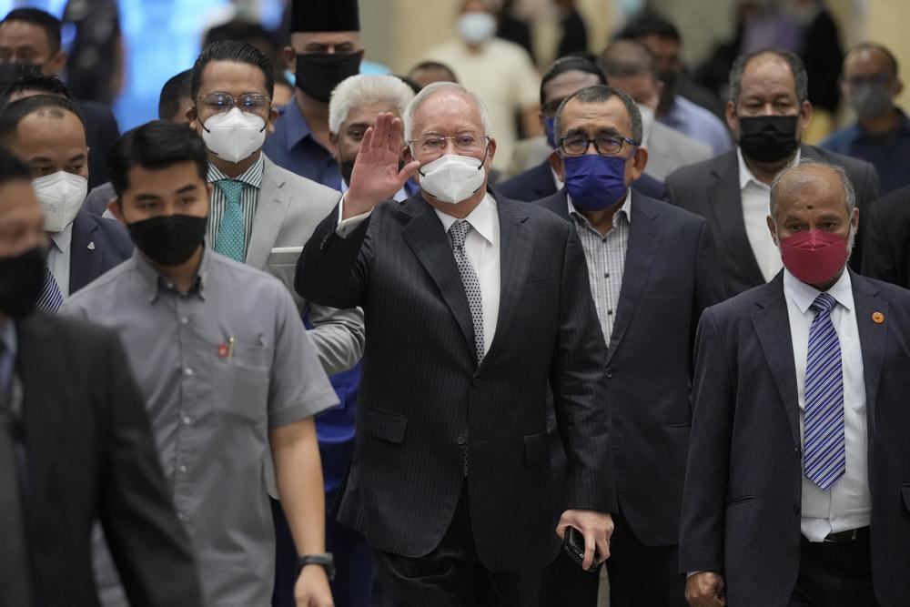 Former Malaysian Prime Minister Najib Razak, center, wearing a face mask, waves as he arrives at Court of Appeal in Putrajaya, Malaysia, Tuesday, Aug. 23, 2022. Najib was sentenced to 12 years in jail by a high court in July 2020, after being found guilty of abuse of power, criminal breach of trust and money laundering for illegally receiving 42 million ringgit ($9.4 million) from SRC International, a former unit of 1MDB. (AP Photo/Vincent Thian)