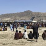 FILE – Hundreds of people gather near a U.S. Air Force C-17 transport plane at the perimeter of the international airport in Kabul, Afghanistan, Aug. 16, 2021. More than a year after the Taliban takeover that saw thousands of Afghans rushing to Kabul’s international airport amid the chaotic U.S. withdrawal, Afghans at risk who failed to get on evacuation flights say they are still struggling to find safe and legal ways out of the country. (AP Photo/Shekib Rahmani, File)
