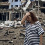 A woman stands amongst the debris after the Russian shelling in Mykolaiv, Ukraine, Wednesday, Aug. 3, 2022. Russian forces kept up their bombardment of the southern Ukrainian city of Mykolaiv, shelling it twice over the past 24 hours, Mykolaiv regional governor Vitaliy Kim reported. The shelling damaged a pier, an industrial enterprise, residential buildings, a garage cooperative, a supermarket and a pharmacy, Kim said. (AP Photo/Kostiantyn Liberov)
