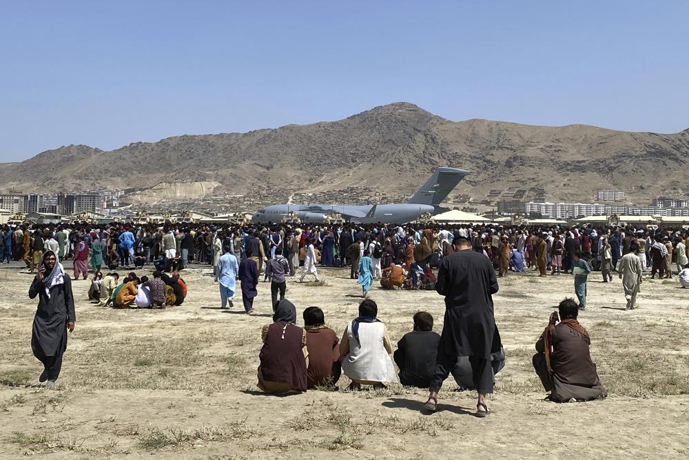 FILE – Hundreds of people gather near a U.S. Air Force C-17 transport plane at the perimeter of the international airport in Kabul, Afghanistan, on Aug. 16, 2021. The nearly 12 months since the chaotic end to the U.S. war in Afghanistan haven’t been easy for Joe Biden. In the summer of 2021, the American electorate largely approved of the new president’s performance. (AP Photo/Shekib Rahmani, File)