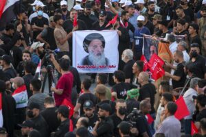 FILE – Supporters of Iran-backed Shiite Coordination Framework attend a rally to denounce their rivals, followers of an influential Shiite cleric Muqtada al-Sadr who stormed the parliament last month and have since been holding a sit-in outside the assembly building in Baghdad, Iraq, Friday, Aug. 12, 2022. On the photo is a revered Shiite Grand Ayatollah Ali al-Sistani. (AP Photo/Anmar Khalil, File)
