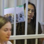 WNBA star and two-time Olympic gold medalist Brittney Griner holds up images as she stands behind bars in a courtroom for a hearing, in Khimki just outside Moscow, Russia, Tuesday, Aug. 2, 2022. Since Brittney Griner last appeared in her trial for cannabis possession, the question of her fate expanded from a tiny and cramped courtroom on Moscow’s outskirts to the highest level of Russia-US diplomacy. (Evgenia Novozhenina/Pool Photo via AP)