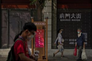 Visitors wearing face masks tour past vacant shop lots at Qianmen Street in Beijing, Wednesday, Aug. 17, 2022. Factories in China’s southwest have shut down after reservoirs used to generate hydropower ran low in a worsening drought, adding to economic strains at a time when President Xi Jinping is trying to extend his position in power. (AP Photo/Andy Wong)
