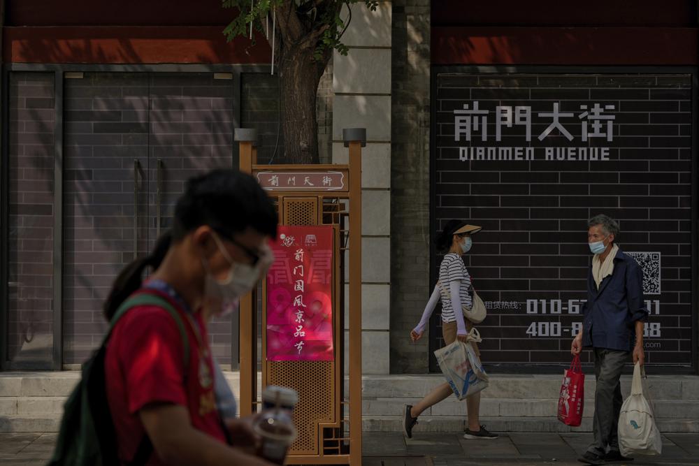 Visitors wearing face masks tour past vacant shop lots at Qianmen Street in Beijing, Wednesday, Aug. 17, 2022. Factories in China’s southwest have shut down after reservoirs used to generate hydropower ran low in a worsening drought, adding to economic strains at a time when President Xi Jinping is trying to extend his position in power. (AP Photo/Andy Wong)