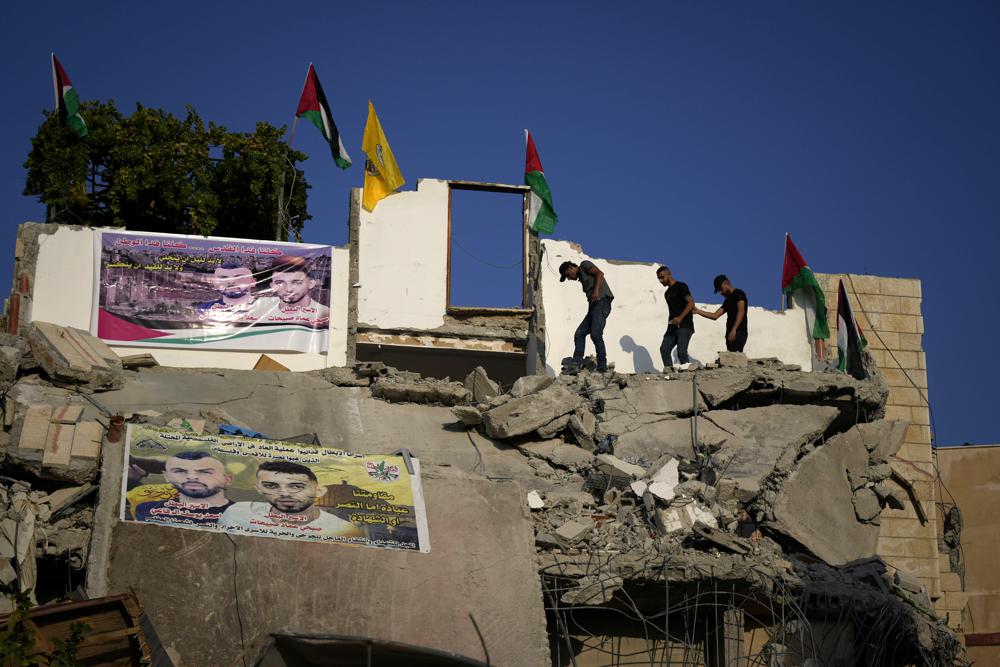 Palestinians clamber over the rubble of the house of Subhi Sbeihat after it was demolished by Israeli forces along with the house of Asad Rifai, both suspected of carrying out a deadly May 2022 attack on Israelis in the city of Elad, near Tel Aviv, in Rummana, near the West Bank city of Jenin, Monday, Aug. 8, 2022. The Israeli military says their soldiers faced a violent protest during the operation. (AP Photo/Majdi Mohammed)