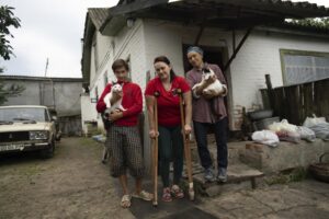 Danyk Rak, 12, his mother Liudmila Koval, centre, and grandmother Nina stand in the village of Voznesenske, near Chernihiv, Ukraine, Saturday, Aug. 13, 2022. Danyk’s family home was destroyed and his mother seriously wounded as Russian forces bombarded Kyiv’s suburbs and surrounding towns in a failed effort to seize the capital. (AP Photo/Evgeniy Maloletka)