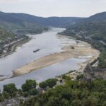 A barge passes exposed rocks and sandbanks on the river Rhine in Bacharach, Germany, Monday, Aug. 15, 2022. After weeks of drought, the water levels of the Rhine have reached historic lows. If the water levels continue to fall, shipping is in danger of coming to a standstill. (Boris Roessler/dpa via AP)