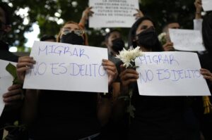 FILE – Women hold signs with a message that reads in Spanish: “Migrating is not a crime,” during a protest outside the Trinidad and Tobago embassy after Trinidad Coast Guard officers were involved in the firing on migrant boat where a Venezuelan baby died and its mother was injured, in Caracas, Venezuela, Feb. 8, 2022. When Mexico imposed a visa requirement on Venezuelans in January, it pushed the migrants onto more dangerous clandestine routes. (AP Photo/Ariana Cubillos, File)