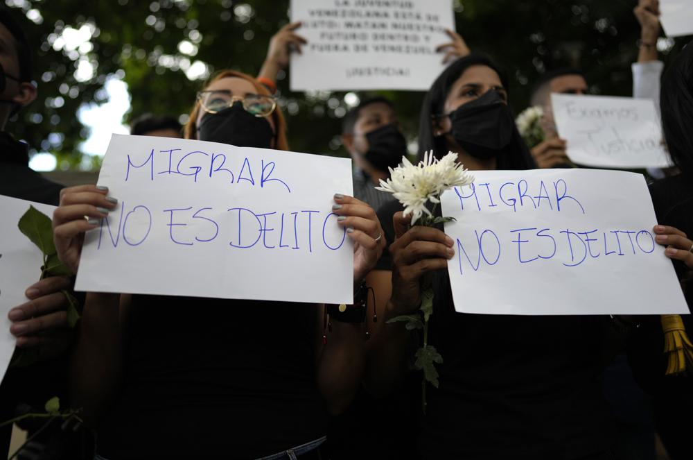 FILE – Women hold signs with a message that reads in Spanish: “Migrating is not a crime,” during a protest outside the Trinidad and Tobago embassy after Trinidad Coast Guard officers were involved in the firing on migrant boat where a Venezuelan baby died and its mother was injured, in Caracas, Venezuela, Feb. 8, 2022. When Mexico imposed a visa requirement on Venezuelans in January, it pushed the migrants onto more dangerous clandestine routes. (AP Photo/Ariana Cubillos, File)