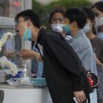 Residents line up to get their routine COVID-19 throat swabs at a coronavirus testing site outside a residential complex in Beijing, Monday, Aug. 29, 2022. (AP Photo/Andy Wong)