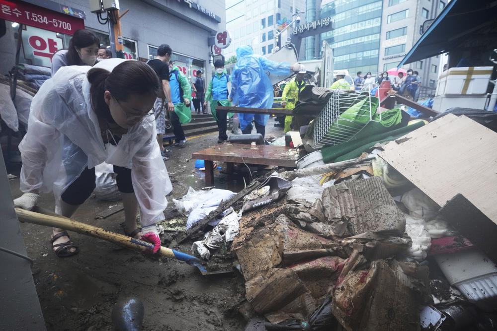 A woman cleans up debris after the water drained from a submerged traditional market following heavy rainfall in Seoul, South Korea, Tuesday, Aug. 9, 2022. Heavy rains drenched South Korea’s capital region, turning the streets of Seoul’s affluent Gangnam district into a river, leaving submerged vehicles and overwhelming public transport systems. (AP Photo/Ahn Young-joon)