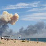 Rising smoke can be seen from the beach at Saky after explosions were heard from the direction of a Russian military airbase near Novofedorivka, Crimea, Tuesday Aug. 9, 2022. The explosion of munitions caused a fire at a military air base in Russian-annexed Crimea Tuesday but no casualties or damage to stationed warplanes, Russia’s Defense Ministry said. (UGC via AP)