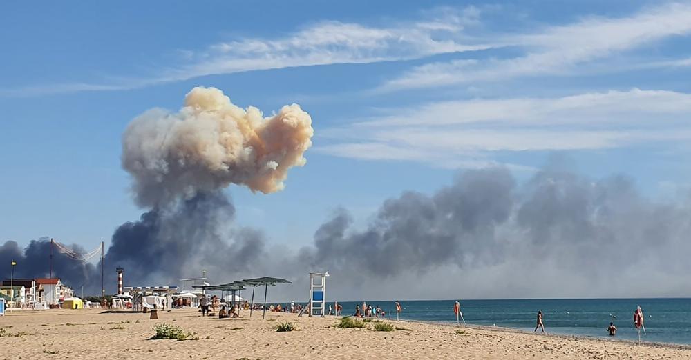 Rising smoke can be seen from the beach at Saky after explosions were heard from the direction of a Russian military airbase near Novofedorivka, Crimea, Tuesday Aug. 9, 2022. The explosion of munitions caused a fire at a military air base in Russian-annexed Crimea Tuesday but no casualties or damage to stationed warplanes, Russia’s Defense Ministry said. (UGC via AP)