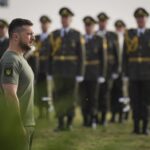 In this photo provided by the Ukrainian Presidential Press Office, Ukrainian President Volodymyr Zelenskyy stands in front of lined up soldiers as he arrives for State Flag Day celebrations in Kyiv, Ukraine, Tuesday, Aug. 23, 2022. (Ukrainian Presidential Press Office via AP)