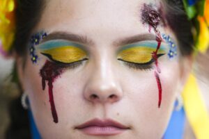 A woman made up with wounds and with Ukrainian colors attends a so called Freedom March demonstration, marking the Ukrainian Independence Day in Berlin, Germany, Wednesday, Aug. 24, 2022. European leaders are pledging unwavering support for Ukraine as the war-torn country marks its Independence Day. The commemorations Wednesday coincide with the six-month milestone of Russia’s invasion. (AP Photo/Markus Schreiber)